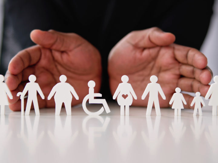 Row of white paper cutouts of diverse people with wheelchair and walking sticks, hands in background